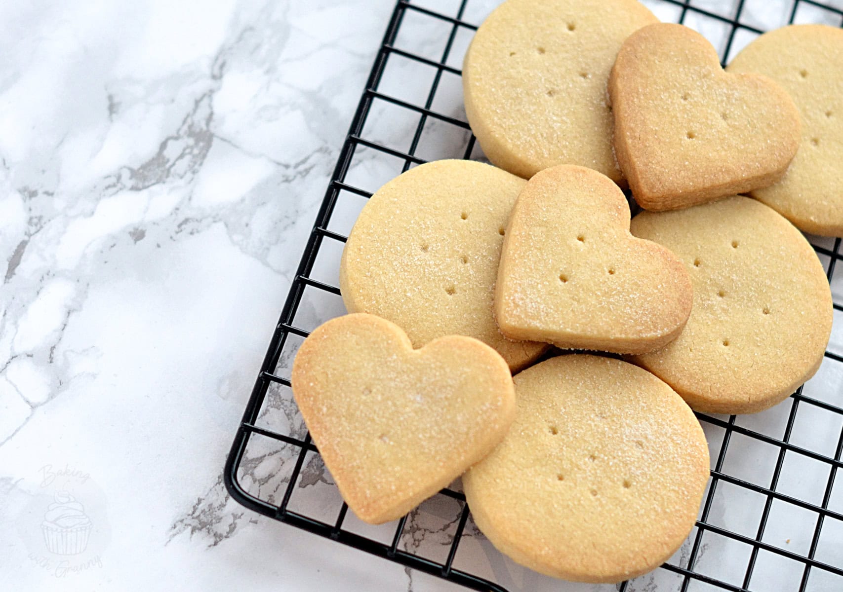 Round and heart-shaped Scottish Shortbread biscuits cooling on a wire rack.