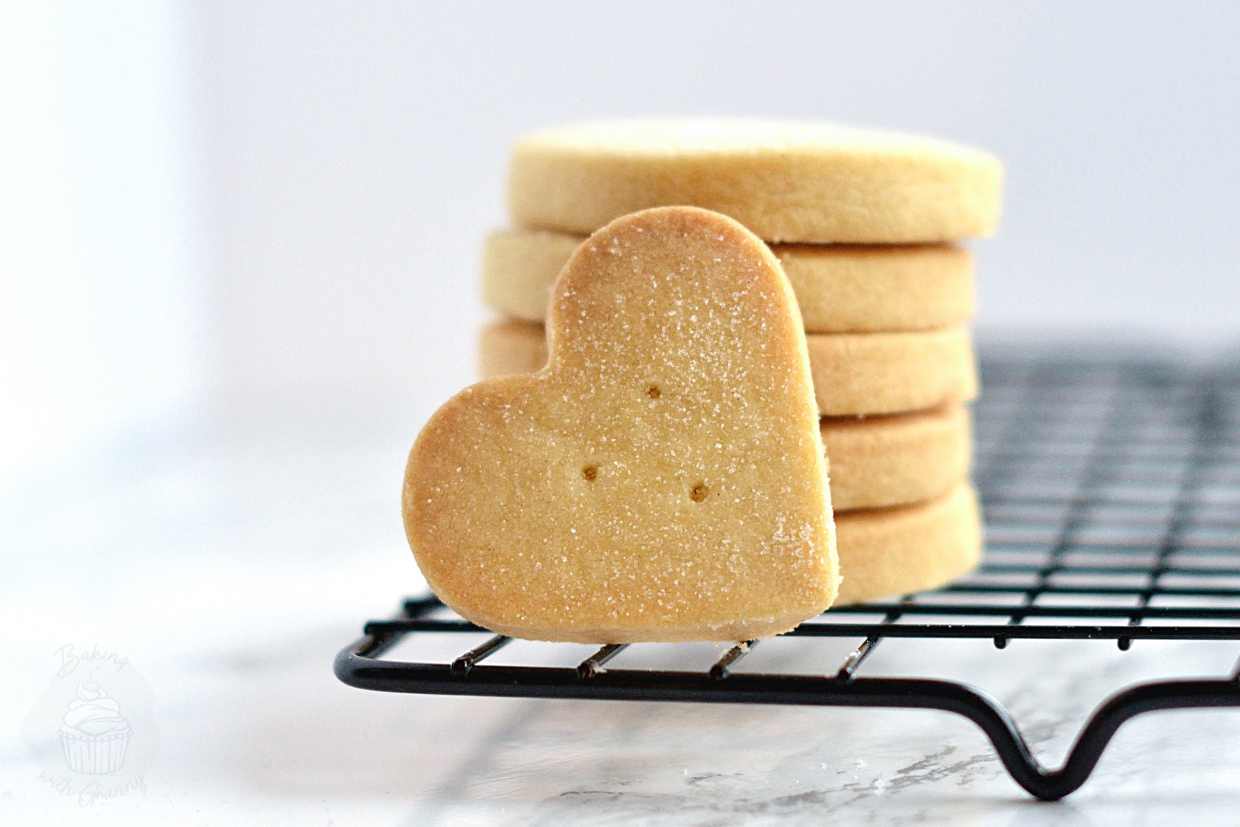 Heart-shaped Scottish Shortbread biscuit in front of a stack of round biscuits.