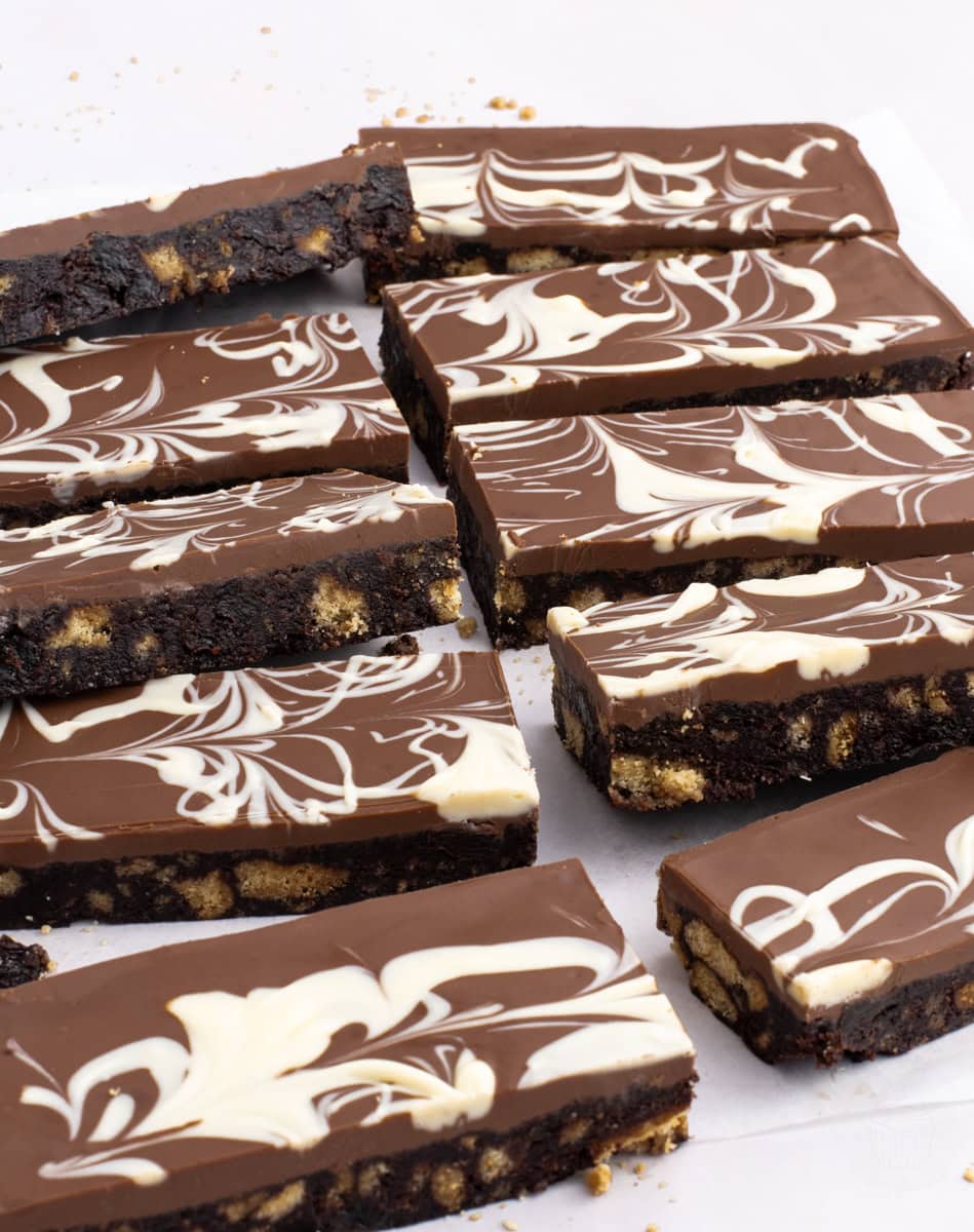 Overhead view of multiple Scottish tiffin slices on white parchment, topped with swirled milk and white chocolate.