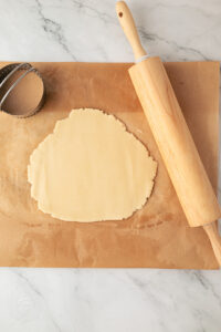 Shortcrust pastry rolled out on baking paper with a rolling pin and fluted cutter