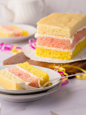 Angel Cake on a wooden board with a slice served in the background.