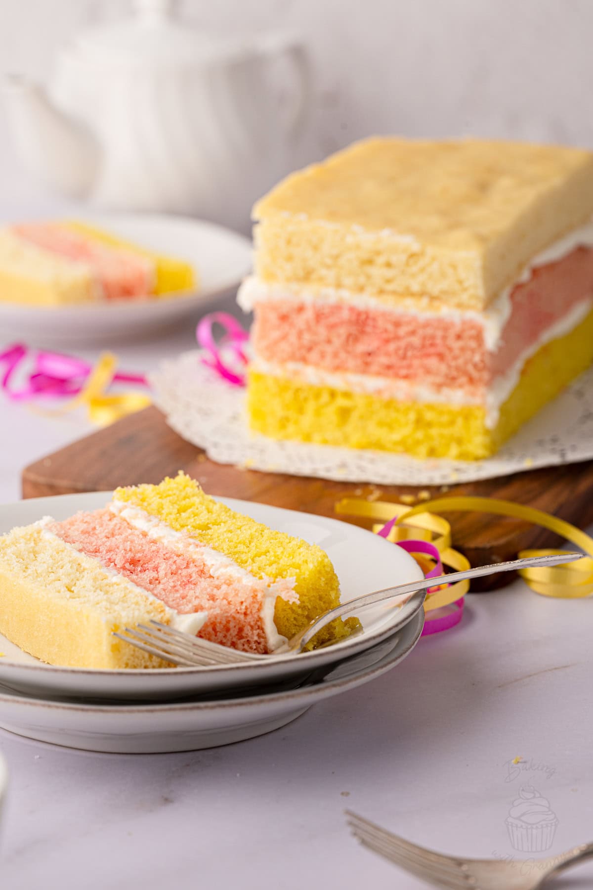 Angel Cake on a wooden board with a slice served in the background.