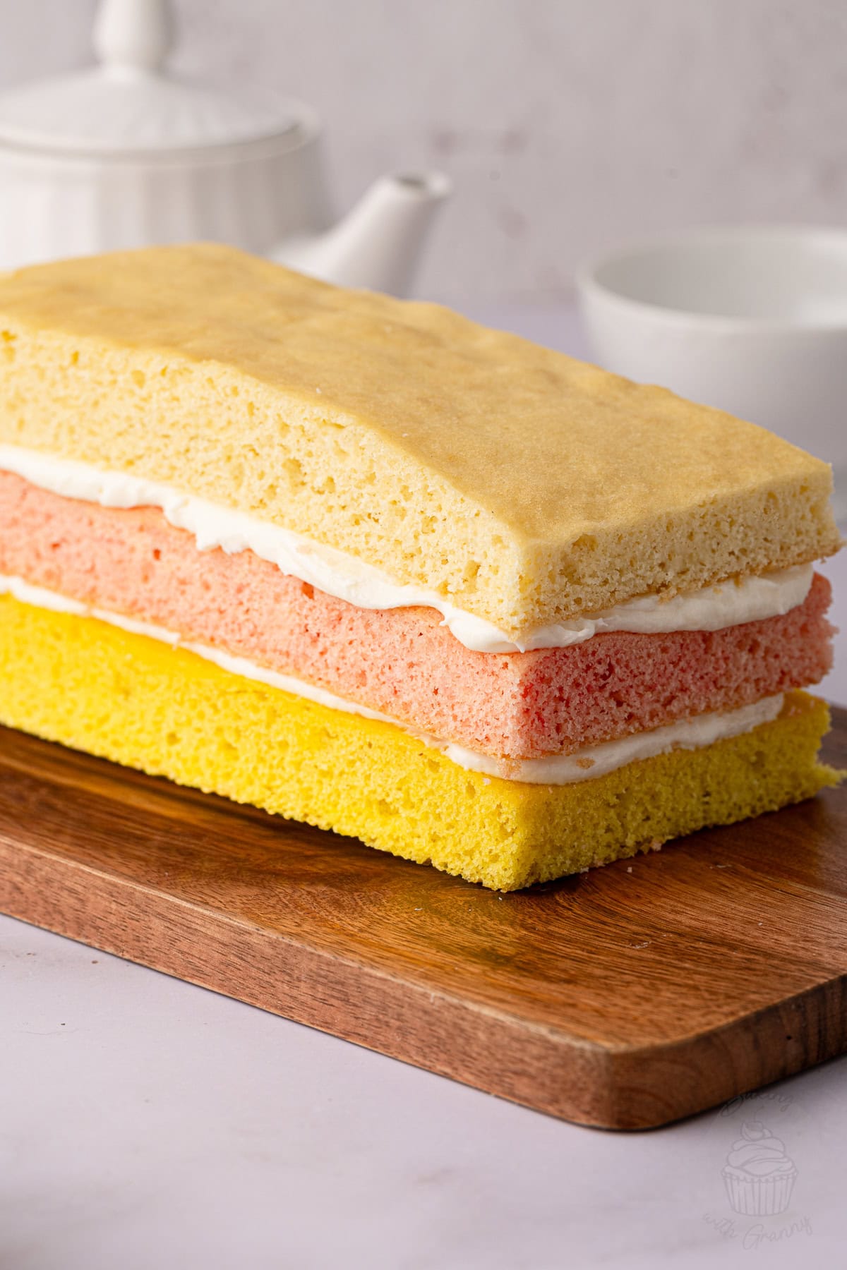 Homemade Angel Cake with vanilla sponge layers coloured pink, yellow and plain, sandwiched with buttercream.
