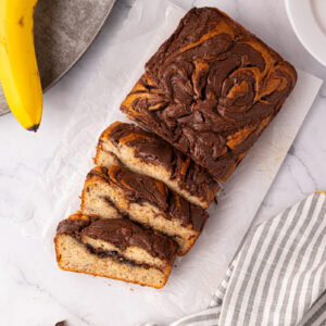Overhead view of banana Nutella loaf cake with slices cut and bananas beside.