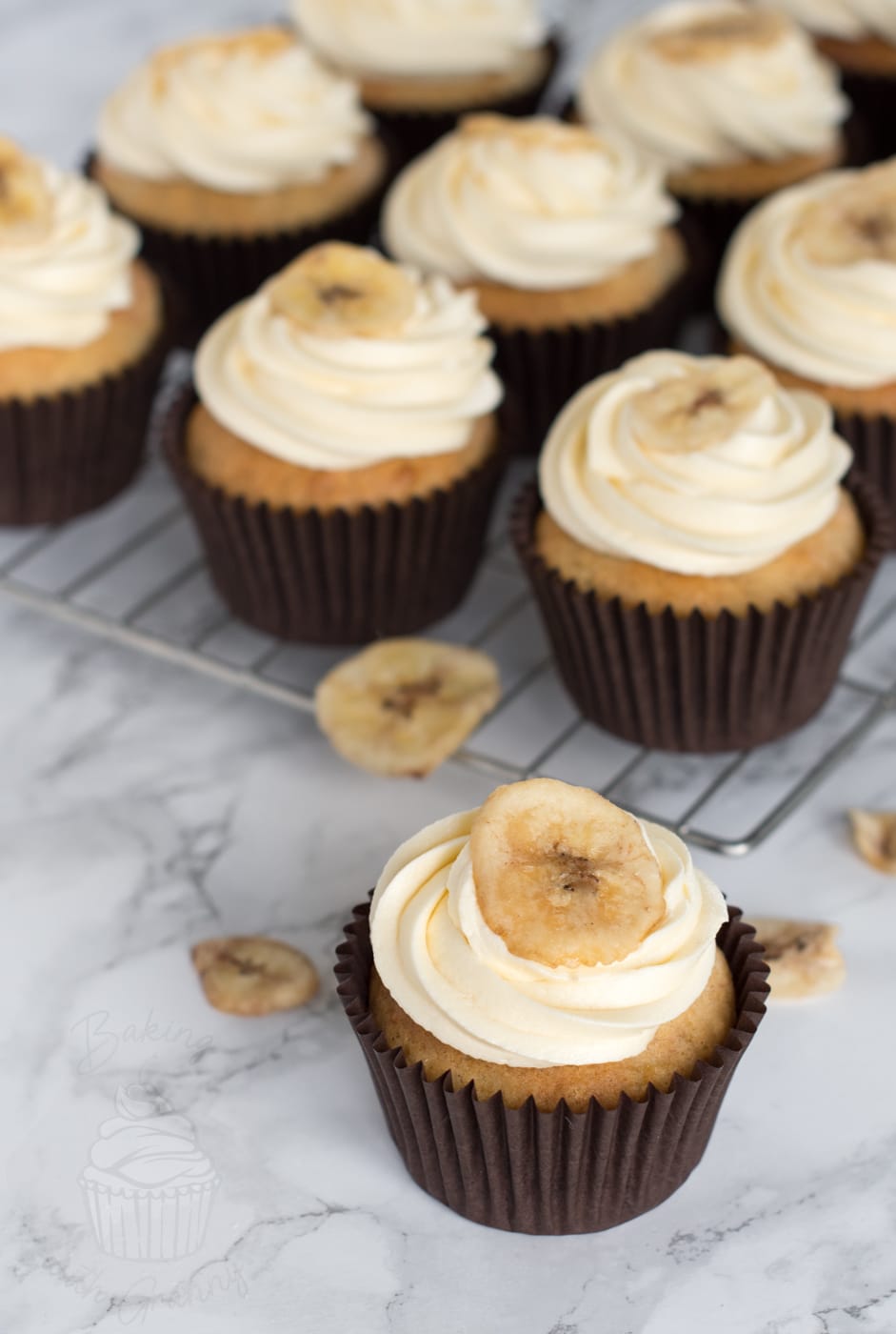 Banana cupcake with vanilla buttercream swirl, in a brown paper case.
