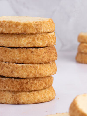 Close-up of a stack of Highlander Shortbread biscuits with crisp golden edges rolled in sugar.