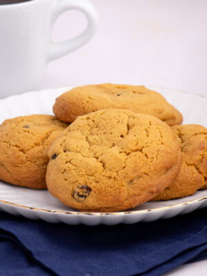 Stack of golden Coffee Buns on a plate with a cup of coffee in the background.