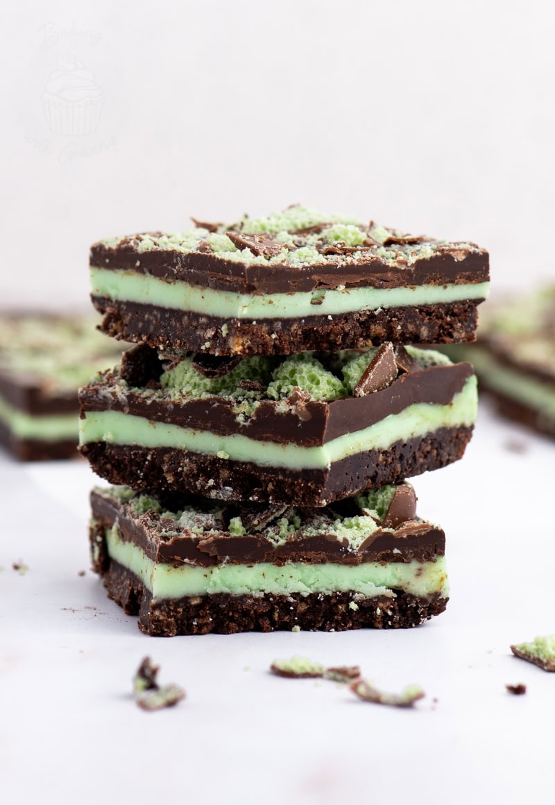 Three pieces of Peppermint Slice stacked to show chocolate topping, peppermint filling, and biscuit base.