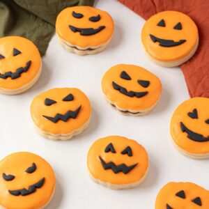 Pumpkin Empire Biscuits with orange icing and black fondant pumpkin faces.