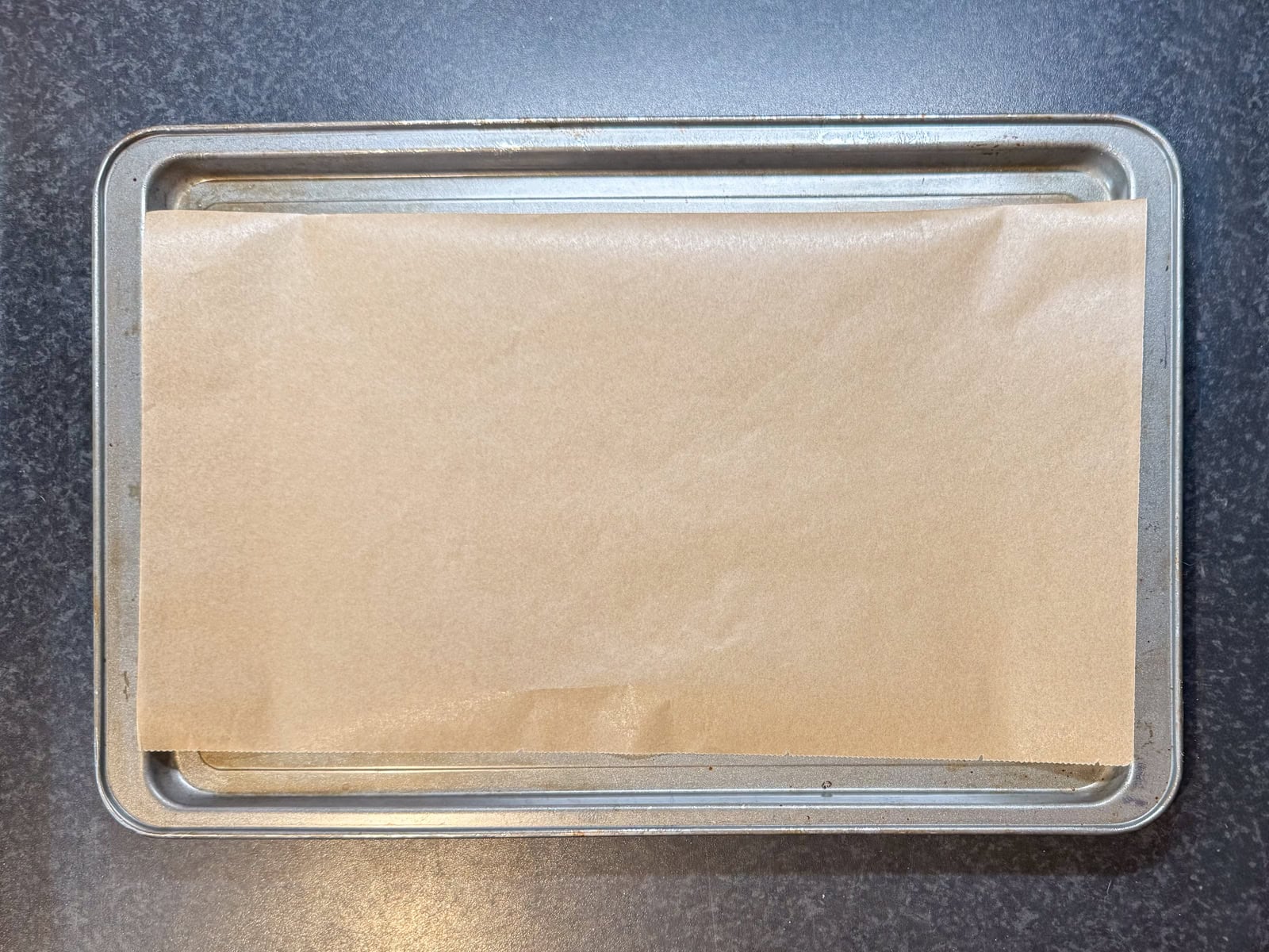 A rectangular baking tin lined with greaseproof paper ready for the biscuit dough.