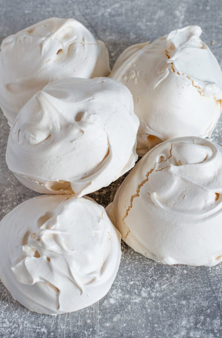 Pile of freshly baked meringues with cracked, glossy shells, part of an easy homemade meringue recipe.