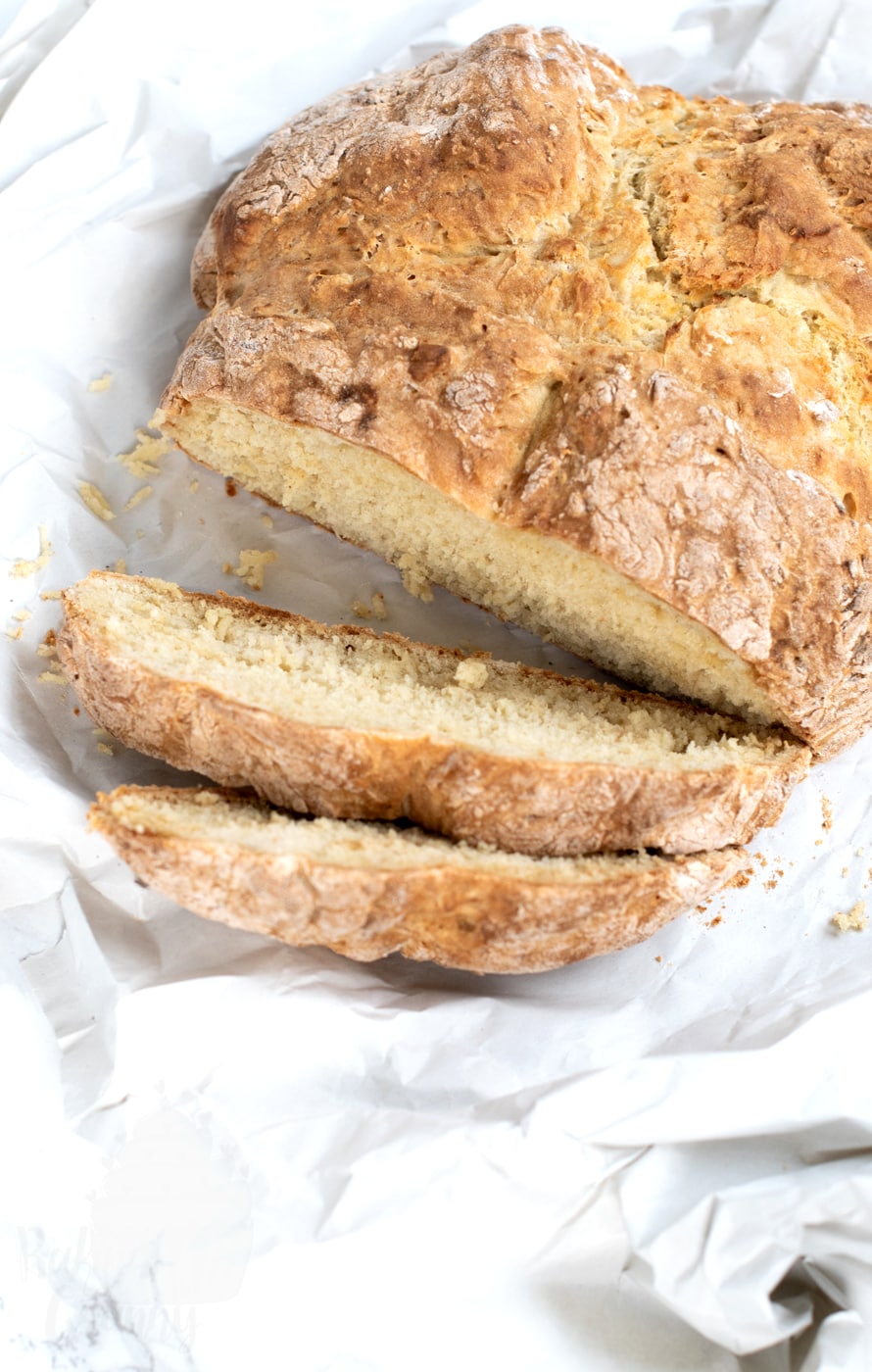 Traditional Irish soda bread loaf sliced on parchment paper, showing the soft crumb inside this easy no-yeast bread recipe, perfect for St Patrick’s Day.