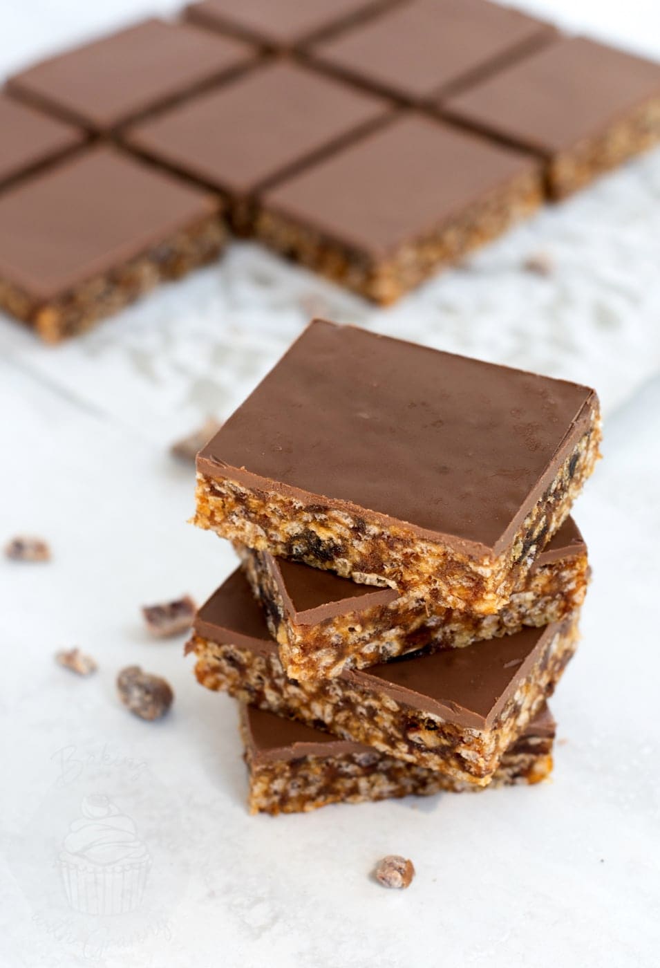 Krispy Date Slice stacked with milk chocolate topping showing chewy date and rice crispy base.