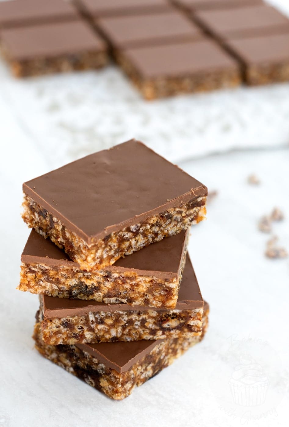 Stacked chocolate topped Krispy Date Slices showing chewy date mixture and crispy texture.