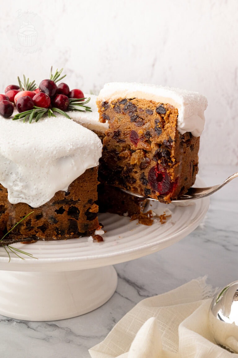 Classic British Christmas cake with a slice being lifted from the cake stand, showing dense fruit cake texture. Traditional UK Christmas cake recipe.