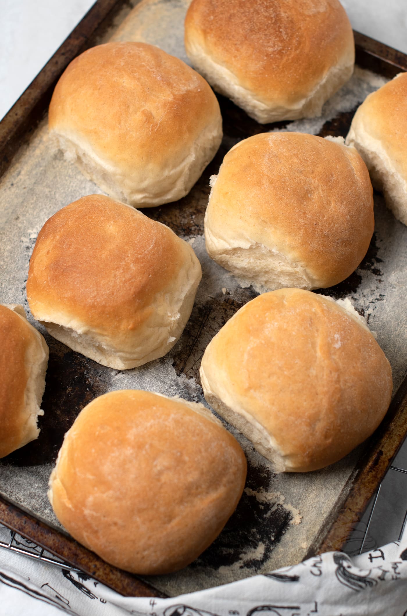 Freshly baked golden brown morning rolls rest invitingly on a baking sheet.