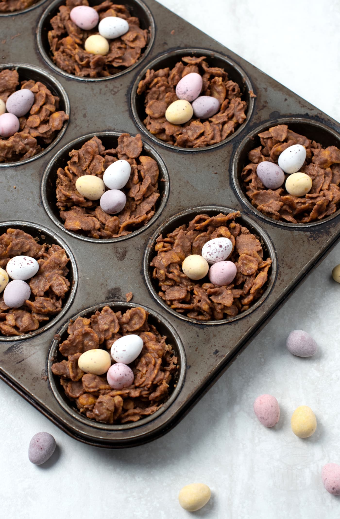 Chocolate Easter nests in a muffin tray topped with mini eggs.