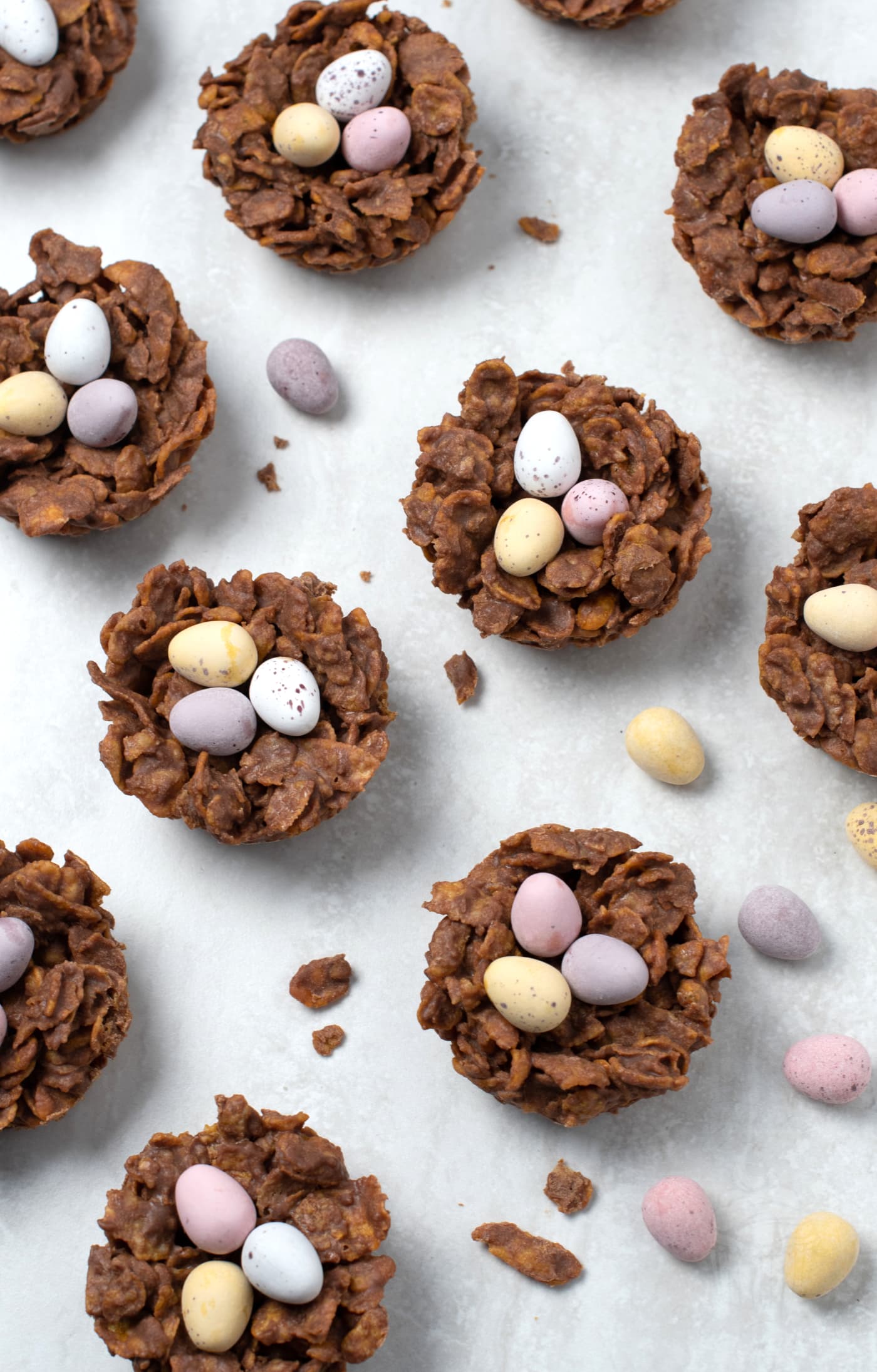 Chocolate Easter nests made with cornflakes and mini eggs on a light background.