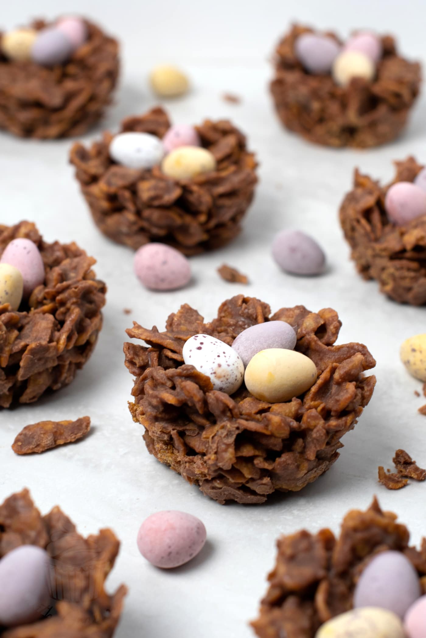 Chocolate Easter nests with mini eggs on a neutral background.