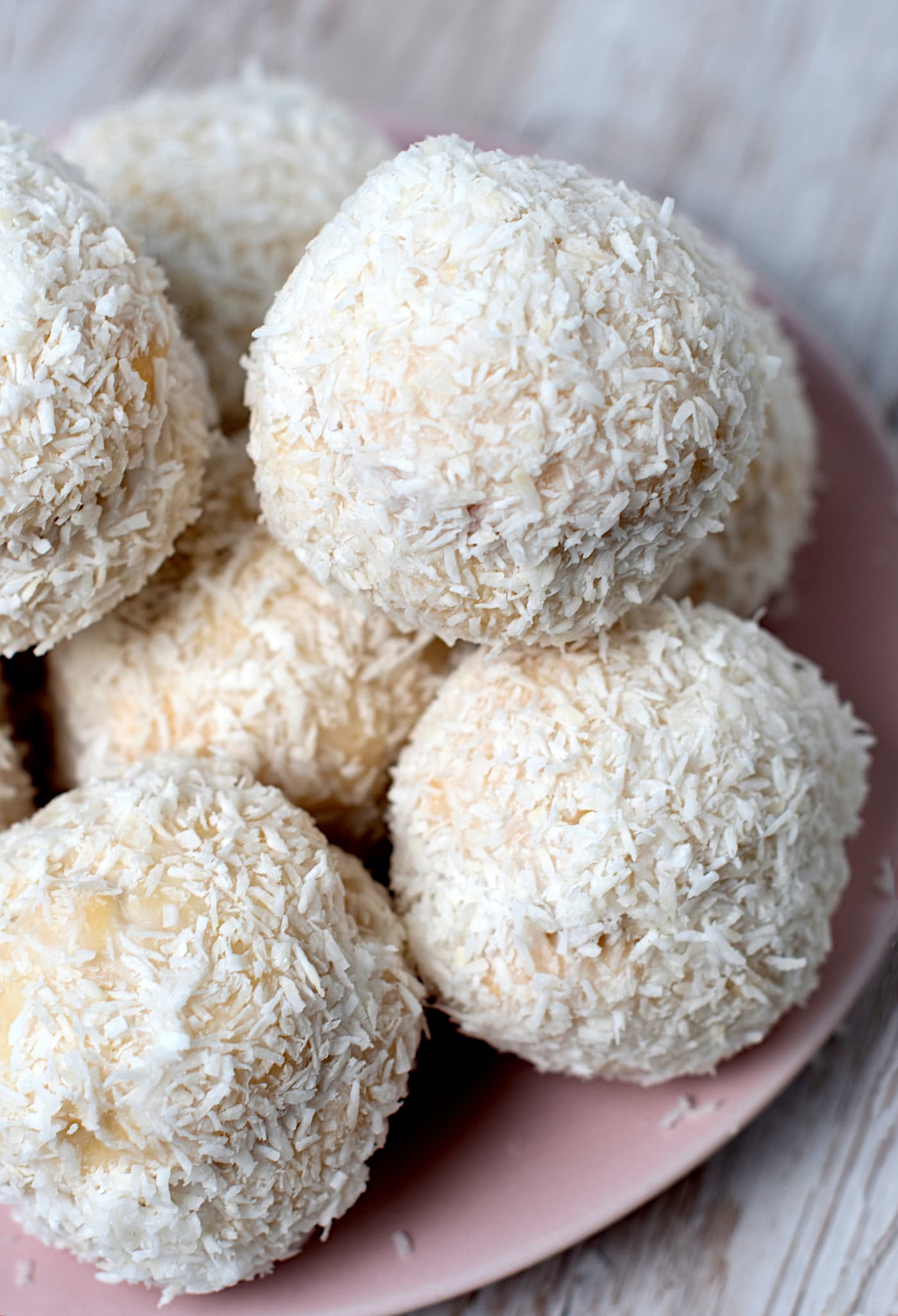 Close-up of homemade Scottish Snowballs - also known as Snowy Joeys - coated in icing and desiccated coconut on a plate.