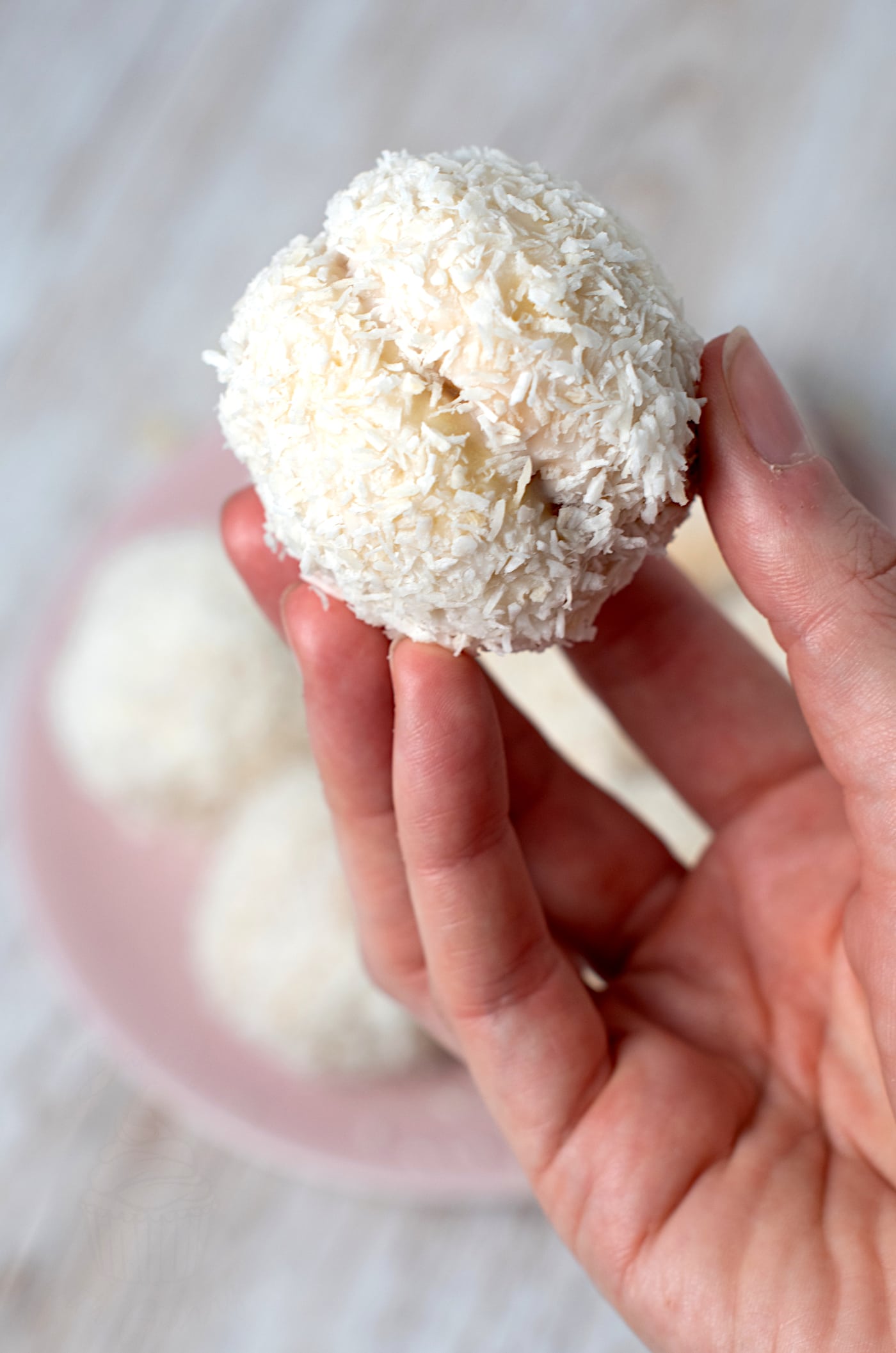 Close-up of a homemade Scottish Snowball (Snowy Joey) coated in icing and desiccated coconut.
