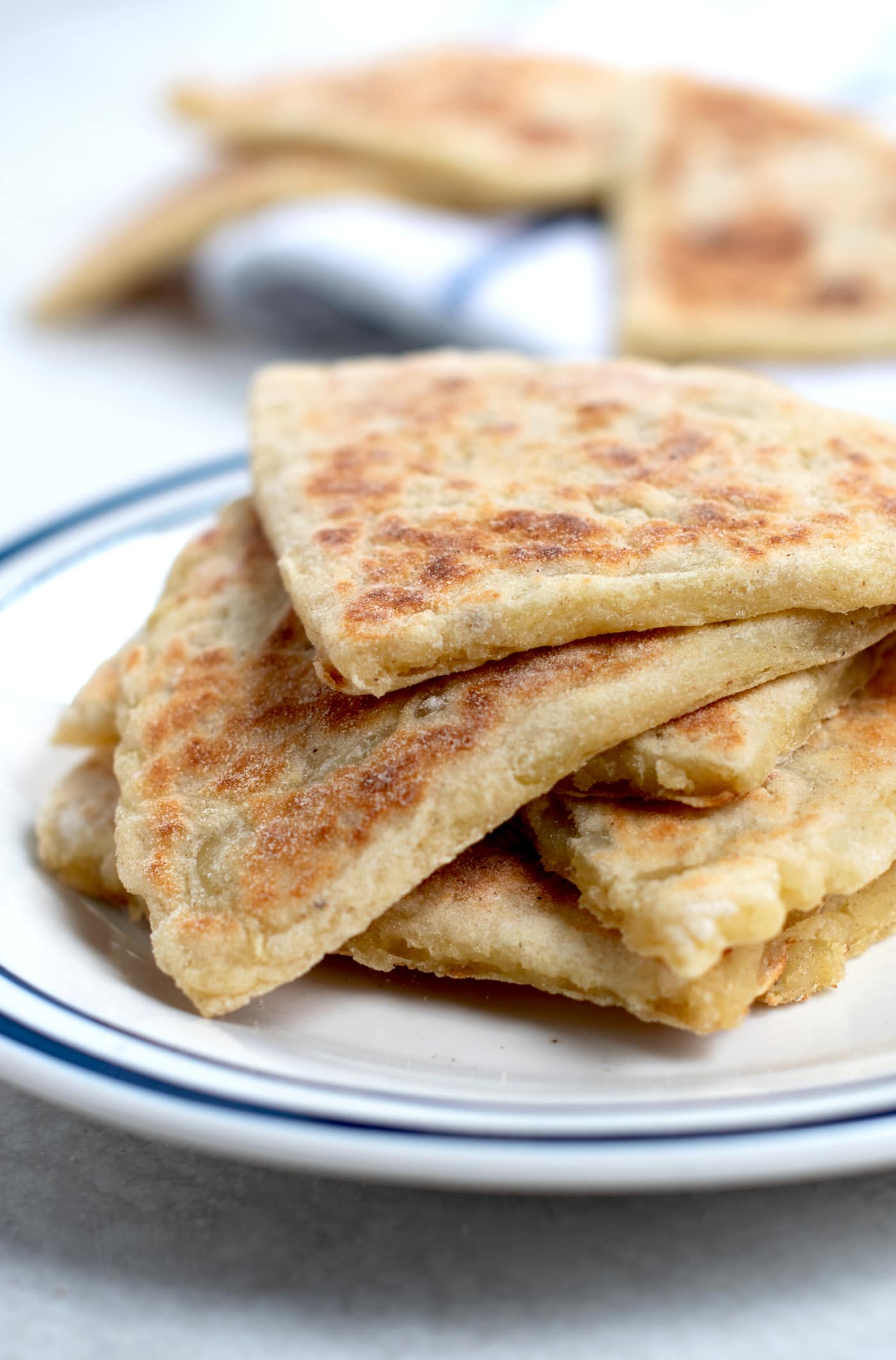 A pile of fresh tattie scones on a plate, with more behind them in the background. Made to a traditional Scottish recipe.