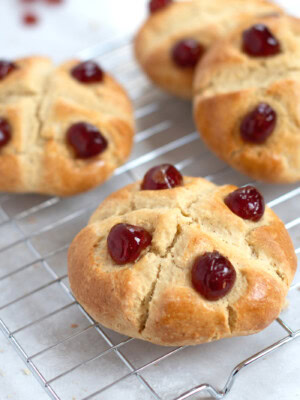 Victoria Scones on a wire rack. Freshly baked golden scones, finished with a cross and glace cherries.