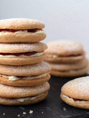 Small stack of Sponge Drop cakes, sandwiched together with fresh cream and strawberry jam. More Sponge Drops can be seen around the stack.