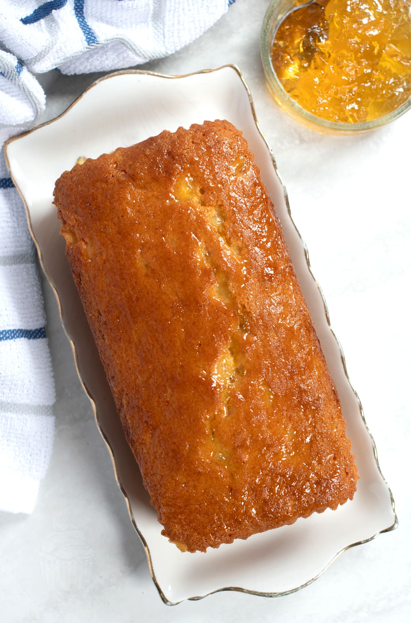 Marmalade Cake made in a loaf tin, served on a vintage plate, with a jar of marmalade to the side.