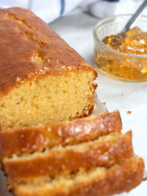 Marmalade cake loaf, sliced into individual portions, with a small jar of open marmalade in the background.