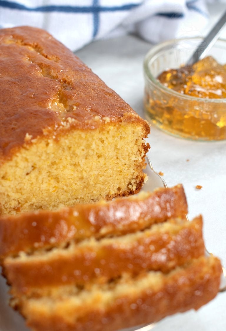 Marmalade cake loaf, sliced into individual portions, with a small jar of open marmalade in the background.