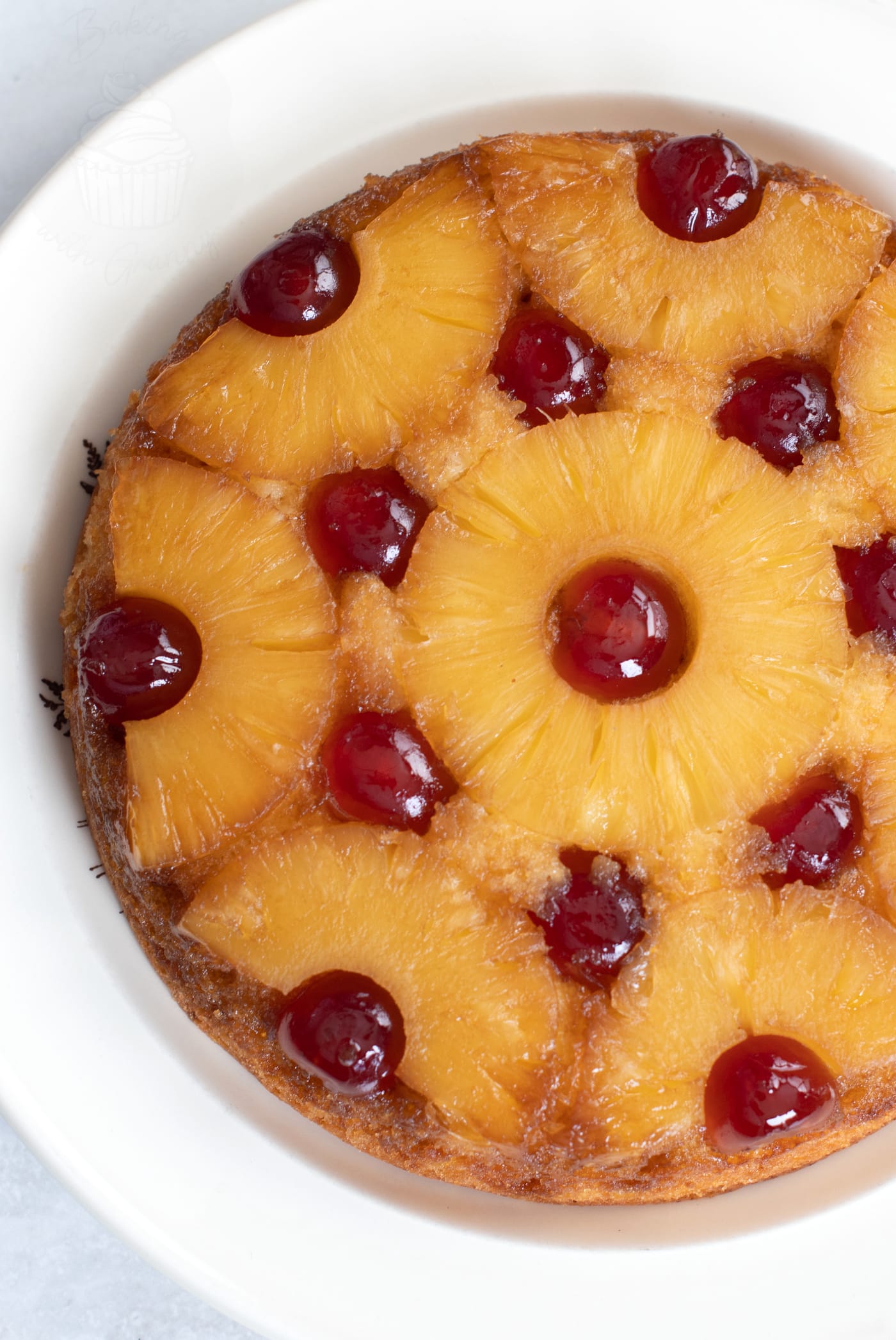 Upside-down Pineapple Cake, with golden pineapple rings, dotted with red glace cherries.