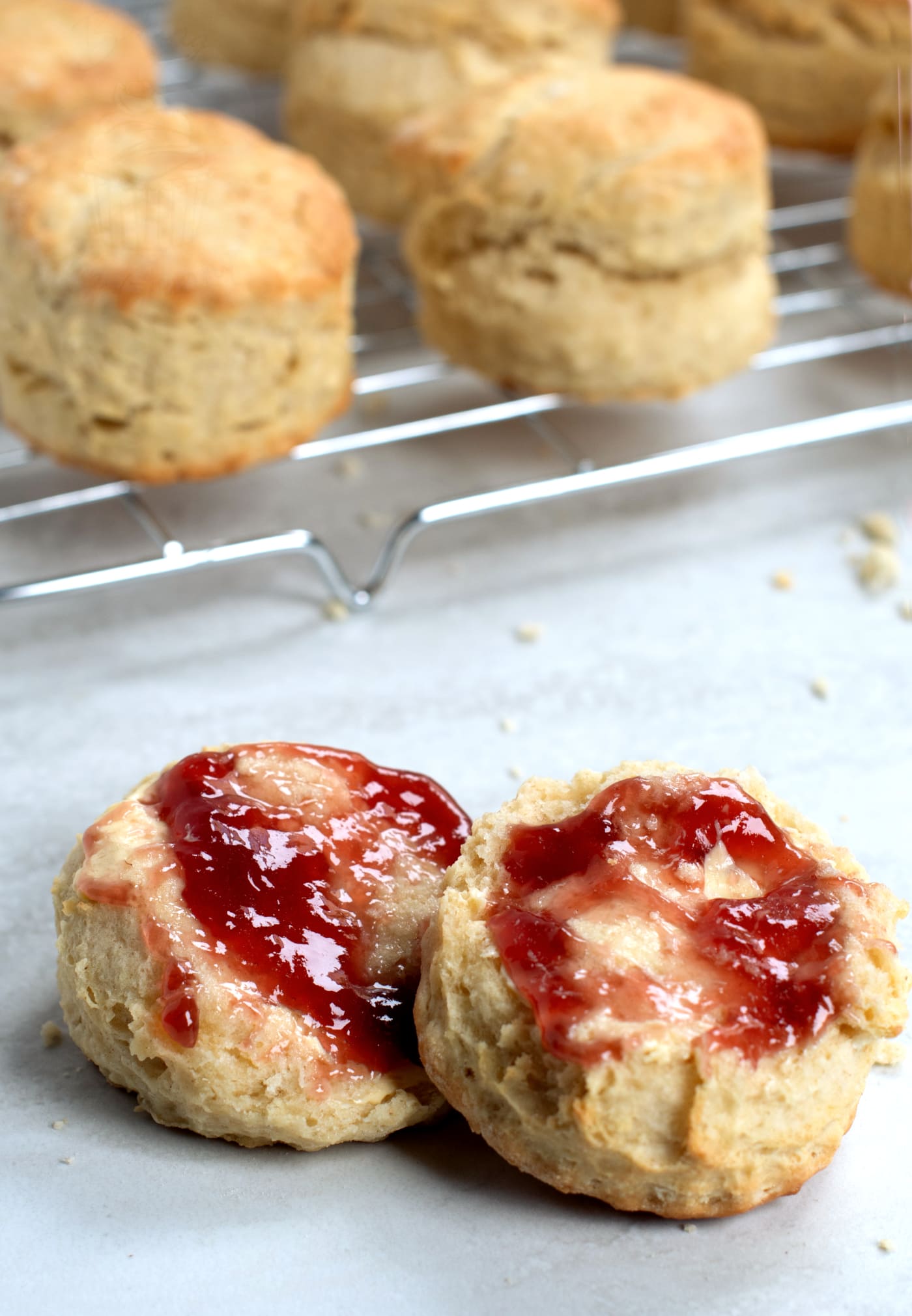 Homemade plain scone split open and topped with butter and strawberry jam.