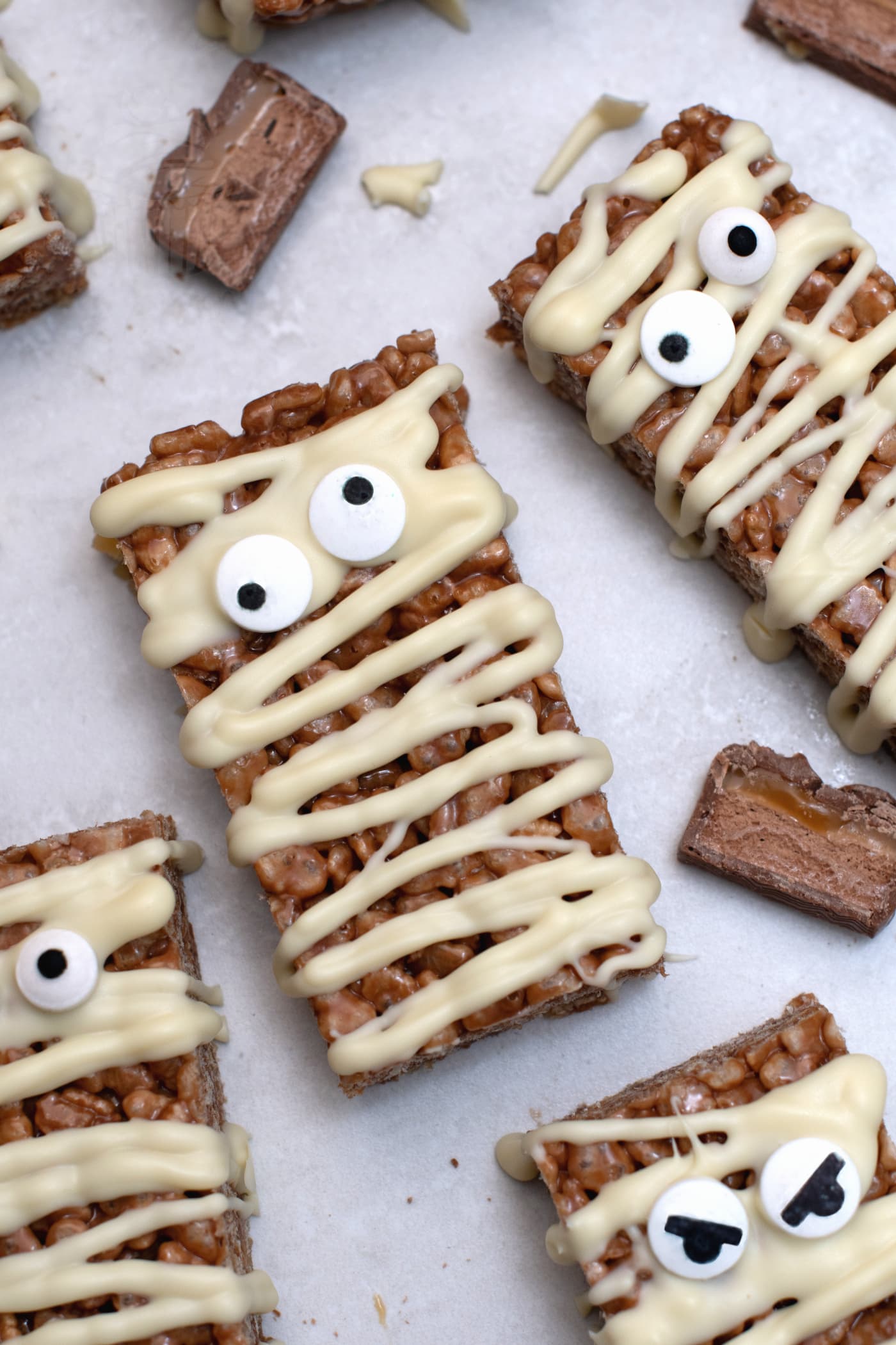 Mummy Mars Bar slices made with rice crispies and melted Mars Bars, decorated as Halloween mummy treats.