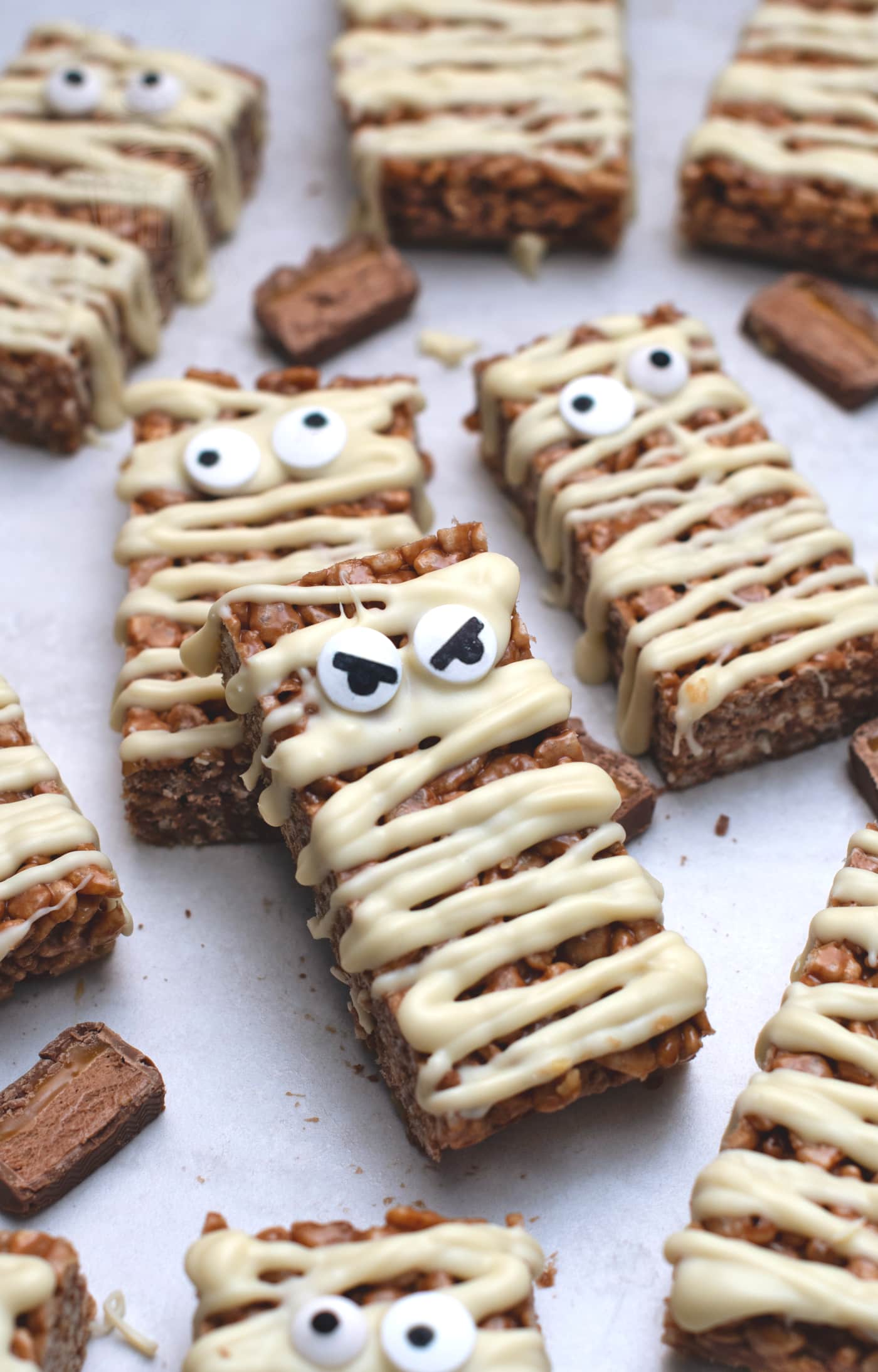 Halloween Mars Bar slice traybake decorated like mummies with white chocolate and candy eyes.