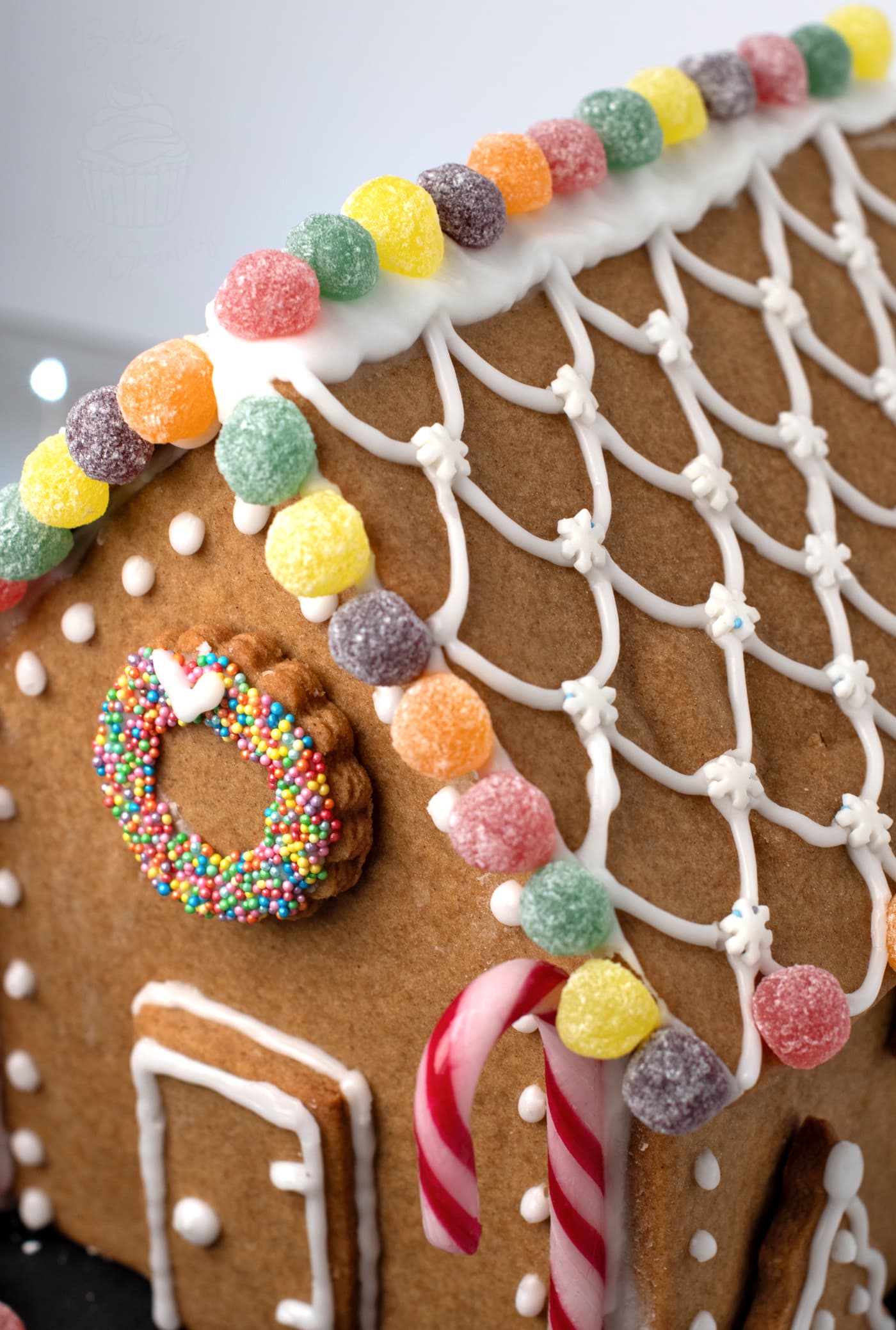 Close-up of the gingerbread house roof decorated with royal icing piping and colourful jelly sweets.