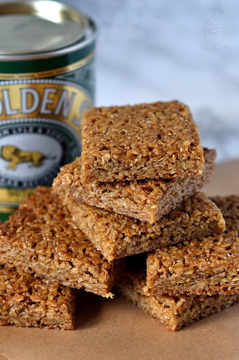 Stack of flapjack squares beside a tin of Lyle’s Golden Syrup.