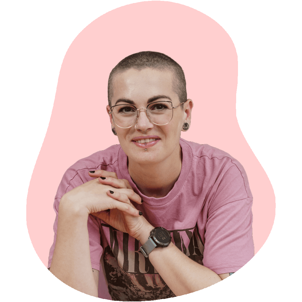 Headshot photo of Amy Reid, the creator of Baking with Granny. Amy has a shaved head, wears glasses and has a pink Nirvana t-shirt on.