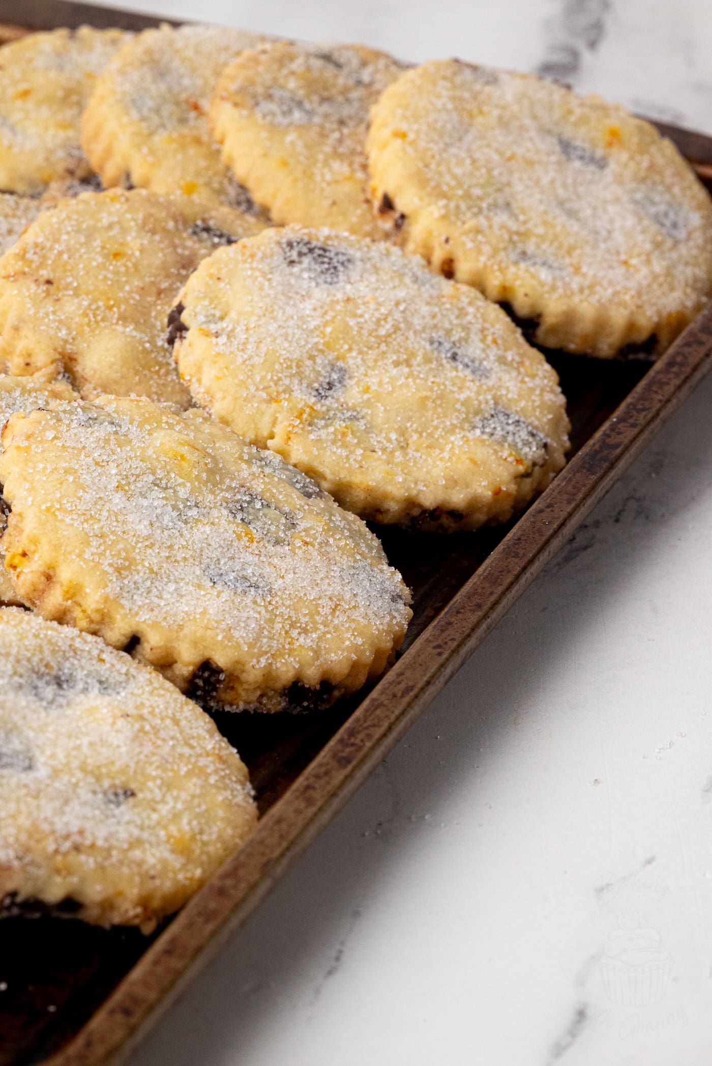 Tray of freshly baked chocolate orange shortbread biscuits, each topped with a generous dusting of sugar.