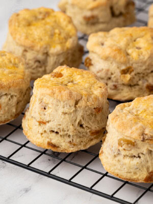Wire rack filled with traditional Fruit Scones, with a pastry cutter in the background.