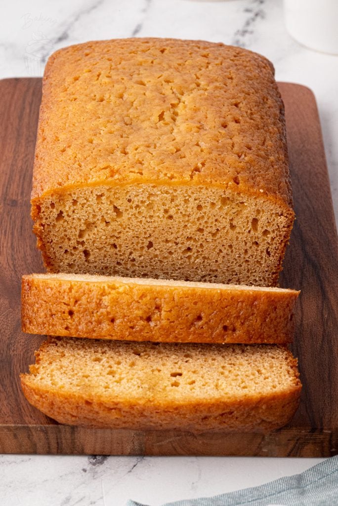 Golden syrup loaf cake sliced on a board with syrup glistening inside.