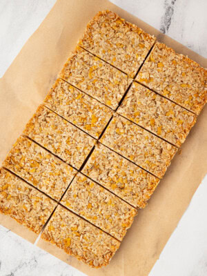 Overhead view of a full tray of honey slice cut into even bars on brown parchment paper.