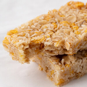 Extreme close-up of a honey slice with a bite taken out, highlighting the soft, chewy oat and coconut texture.