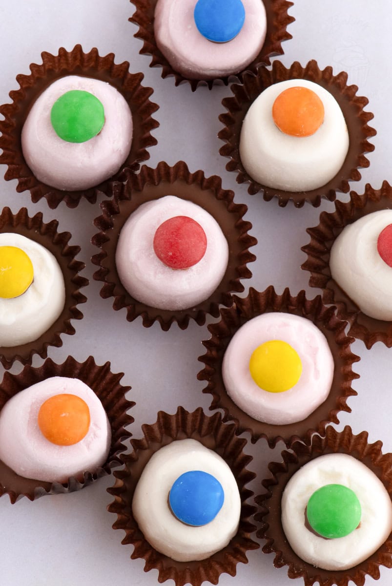 Top-down view of Marshmallow Top Hats with pink and white marshmallows, each finished with a colourful smartie or M&M.