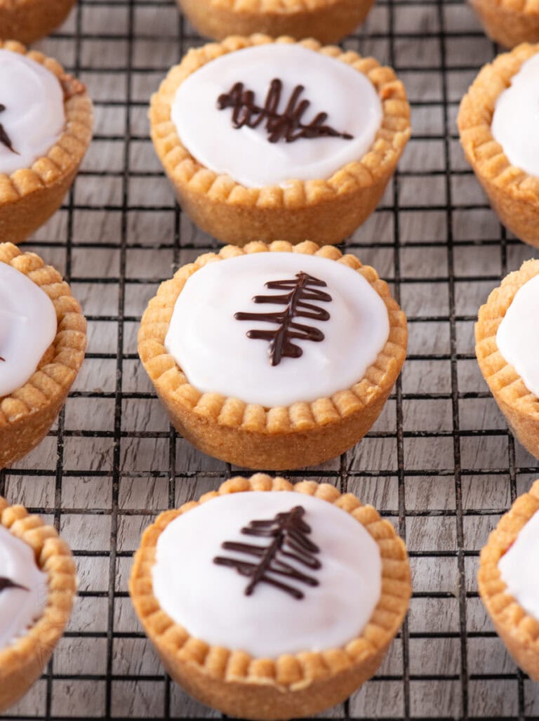 Overhead view of iced Fern Cakes with piped chocolate decorations, arranged neatly on a wire cooling rack.