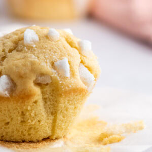 Single Sair Heidie cake unwrapped from its case, topped with pieces of broken sugar cubes and crumbs on the surface below.