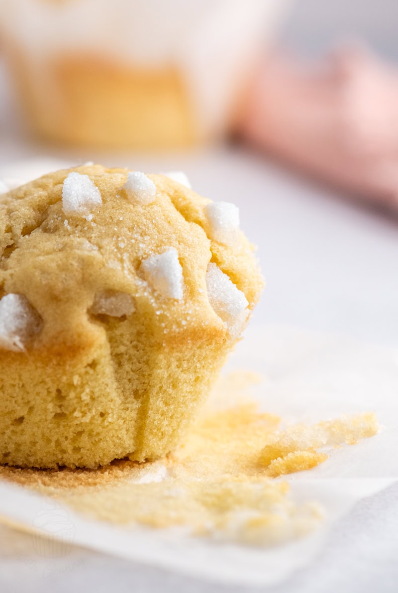 Single Sair Heidie cake unwrapped from its case, topped with pieces of broken sugar cubes and crumbs on the surface below.