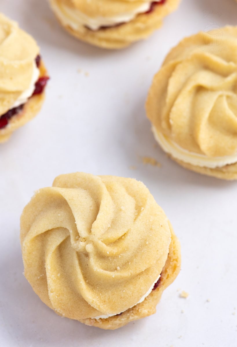 Overhead view of Viennese Whirls showing their piped swirl biscuit tops and creamy jam filling.