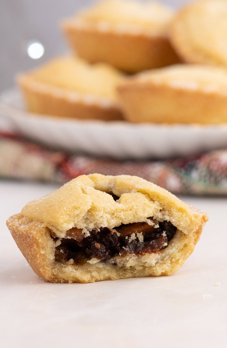 Close-up of a classic mince pie cut in half, showing the rich homemade mincemeat filling inside a crumbly shortcrust pastry.