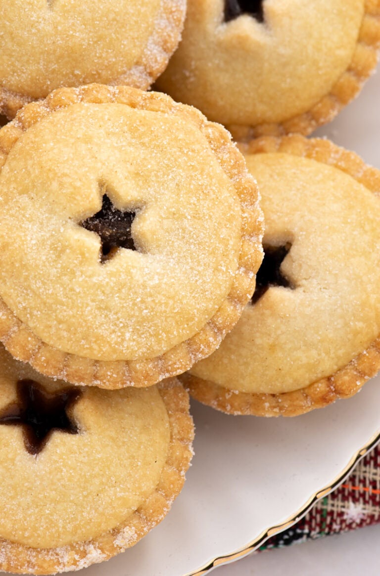 Overhead view of classic mince pies with star-shaped pastry tops, sprinkled with sugar, showing their traditional festive design.